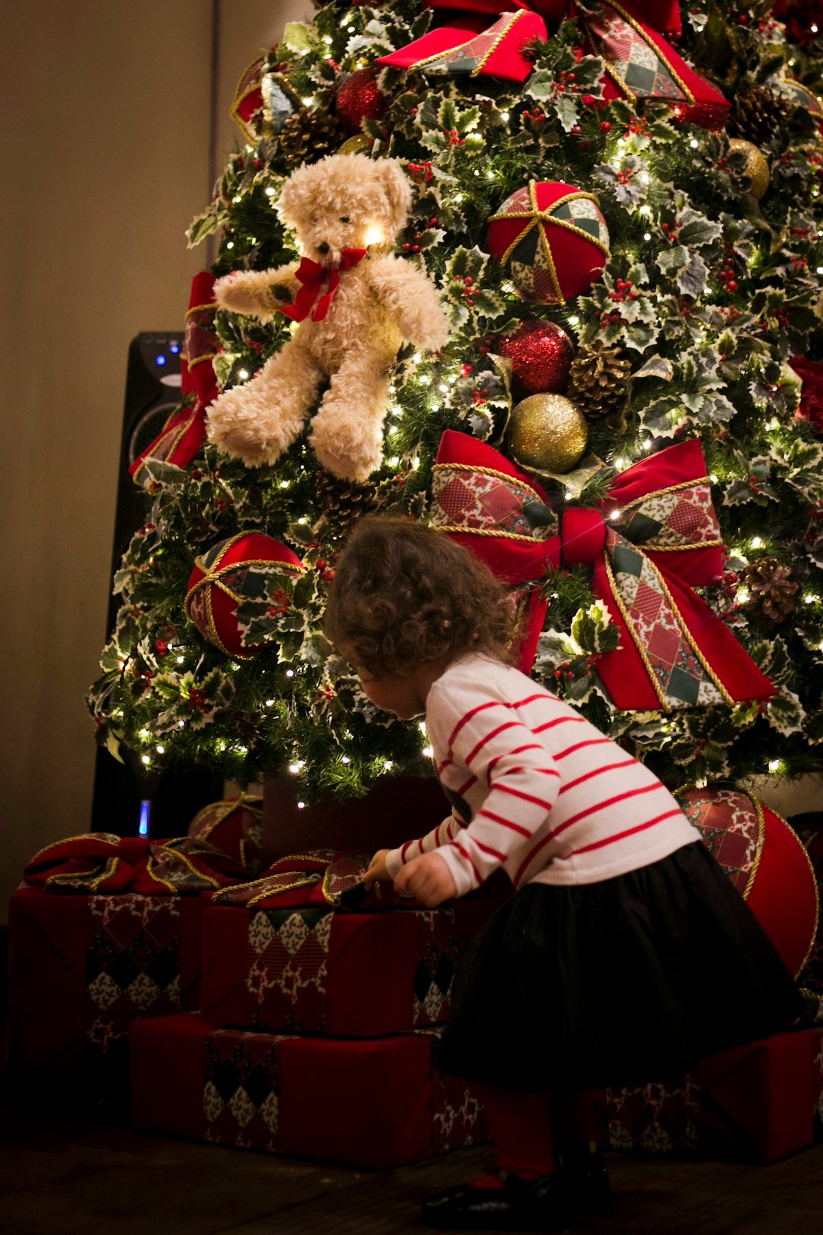 Niña cogiendo un regalo bajo el árbol de Navidad decorado